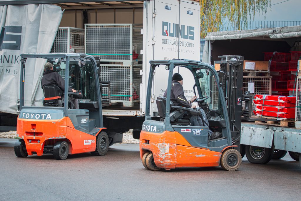 Zwei Stapler entladen gerade jeweils einen LKW.